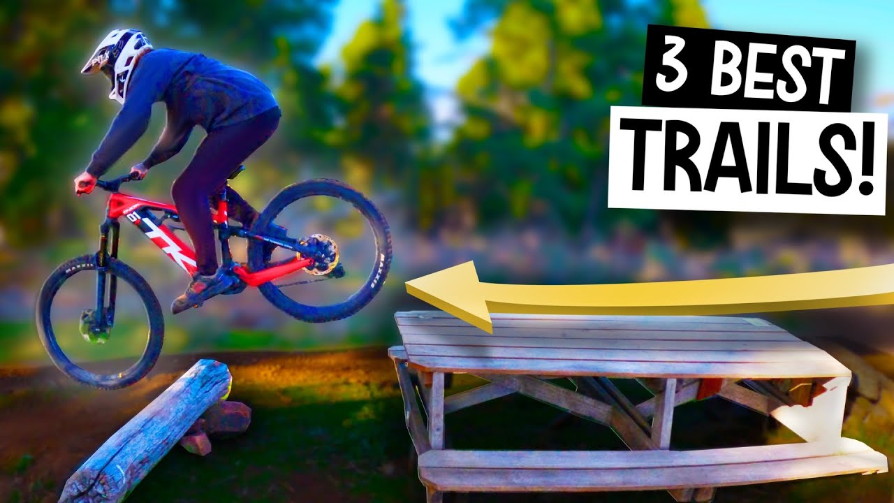 Mountain biker rides across picnic table and jumps off the other side. 